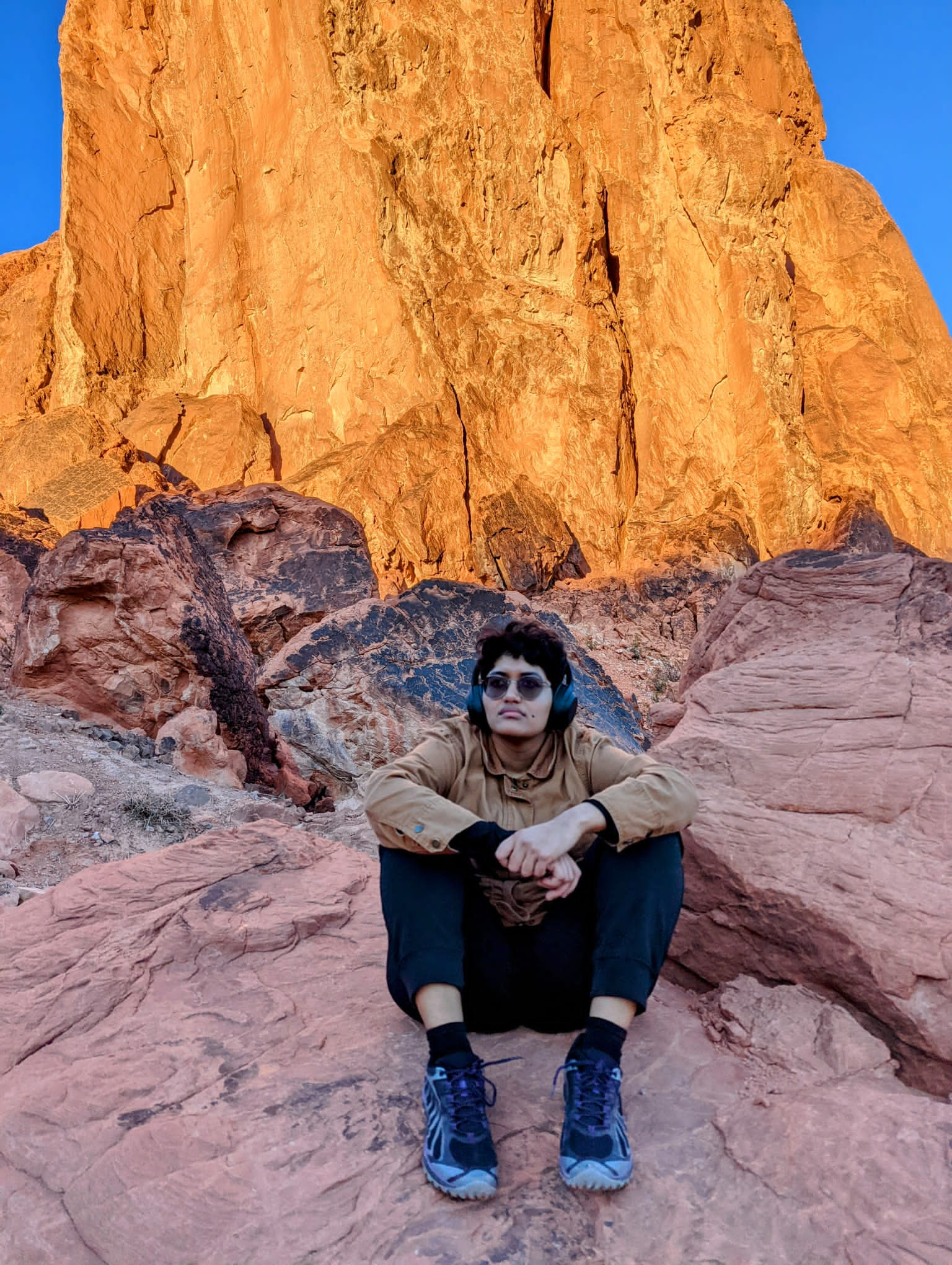 Chandu Avni sits on red sandstone formations. They are looking above.